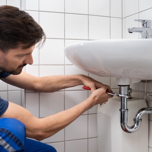Plumber works under sink.